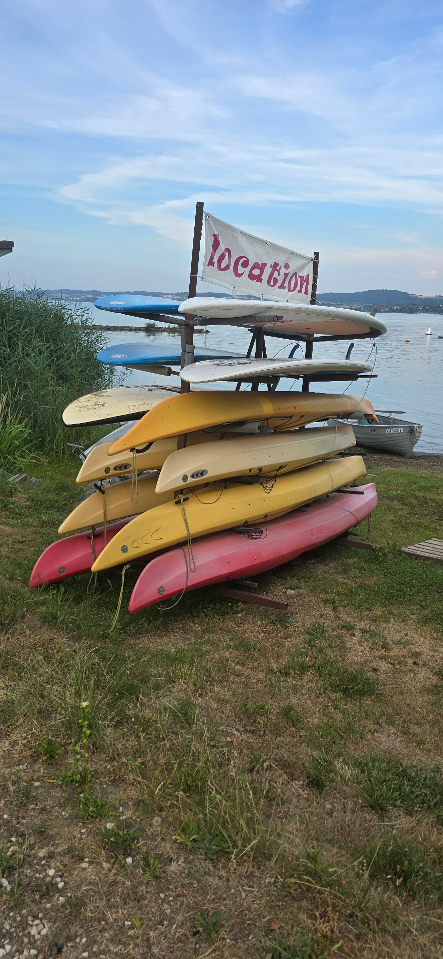 Planches et kayaks empilés sur un rack extérieur exposé au soleil